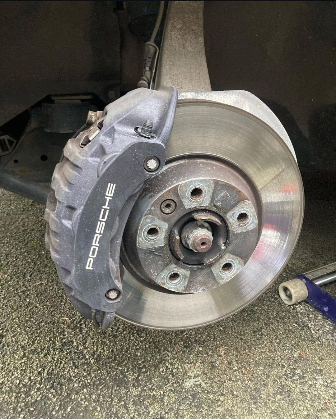 Porsche brake caliper before painting, showing worn original finish