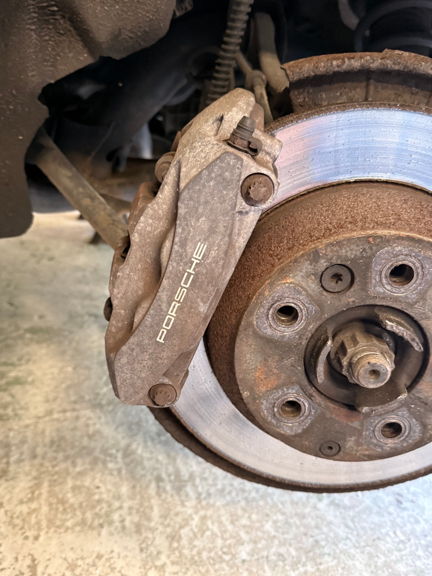 Porsche rear brake caliper before painting, showing corroded grey finish